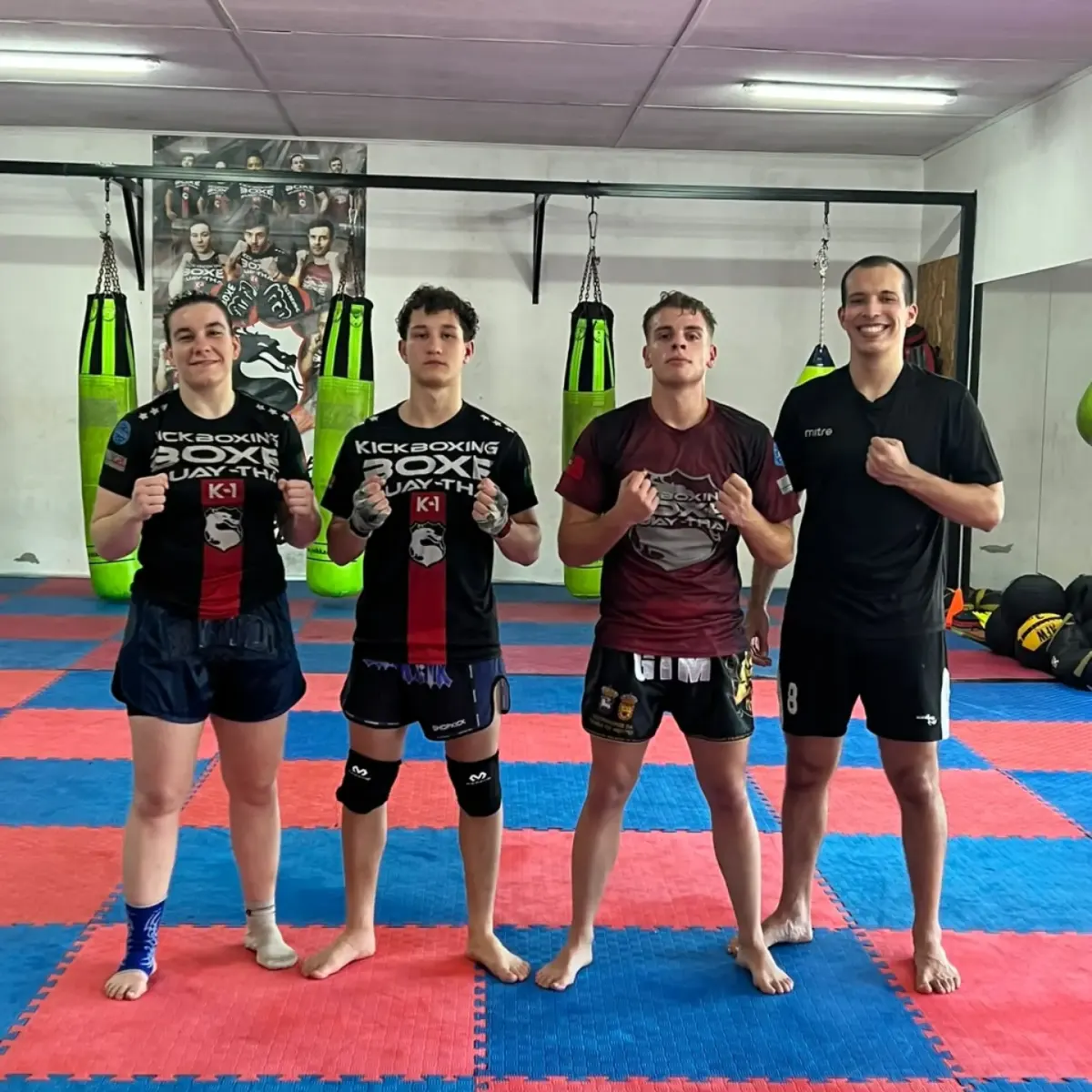 Quatro atletas de MMA em guarda junto aos sacos de boxe verdes