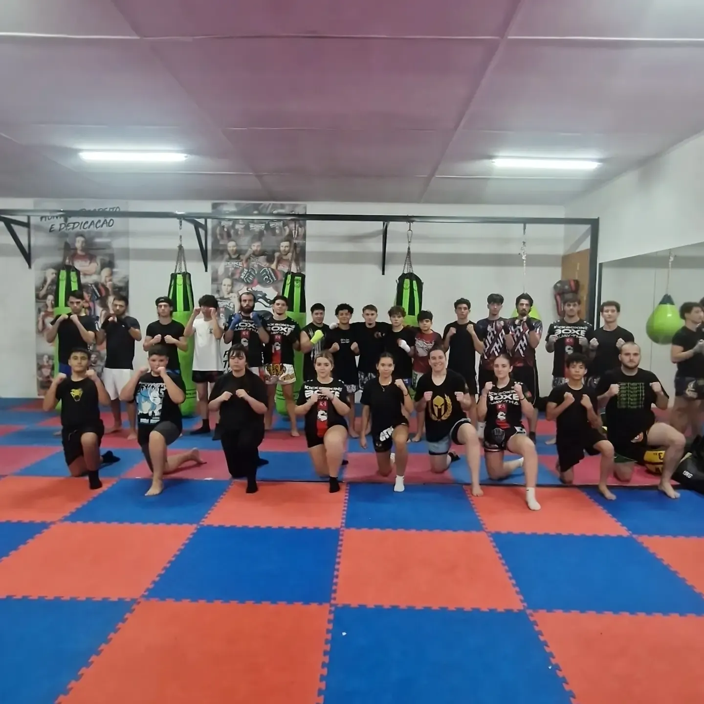 Turma de kickboxing e Muay Thai em guarda no tatame, num treino de segunda-feira